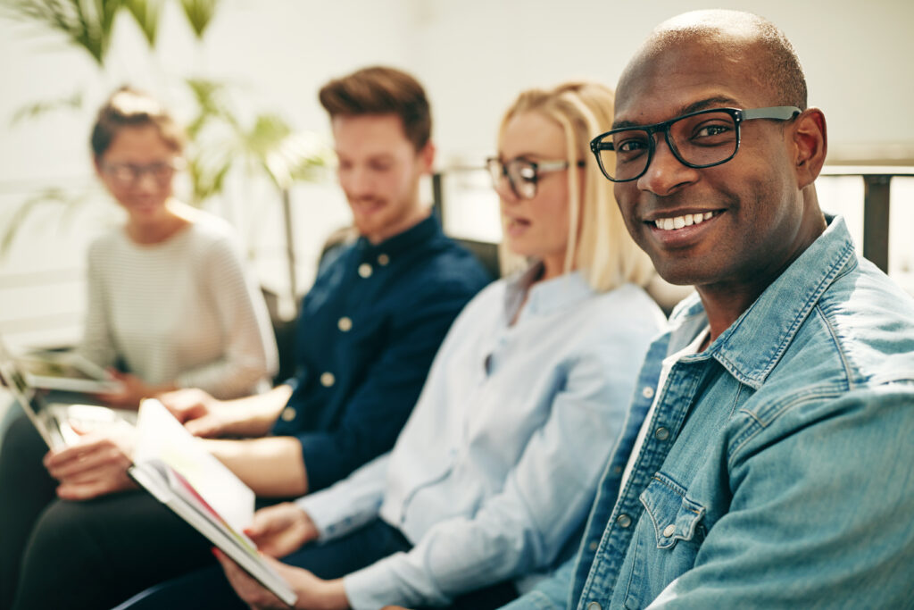 Smiling young African businessman sitting with coworkers in an office