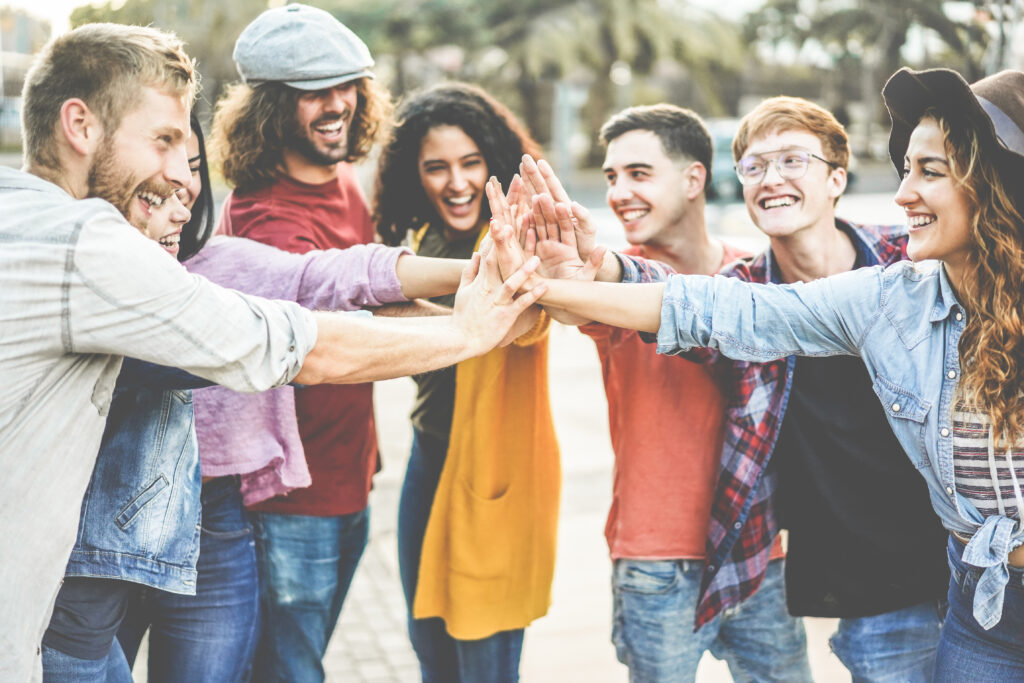 Young millennials friends stacking hands together - Happy students