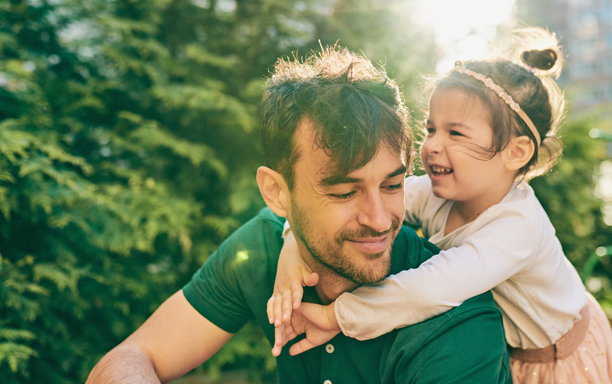 Outdoor image of happy cute little girl smiling and playing with her father