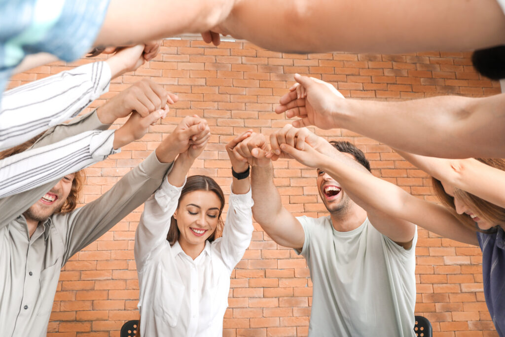 Young people holding hands together at group therapy session