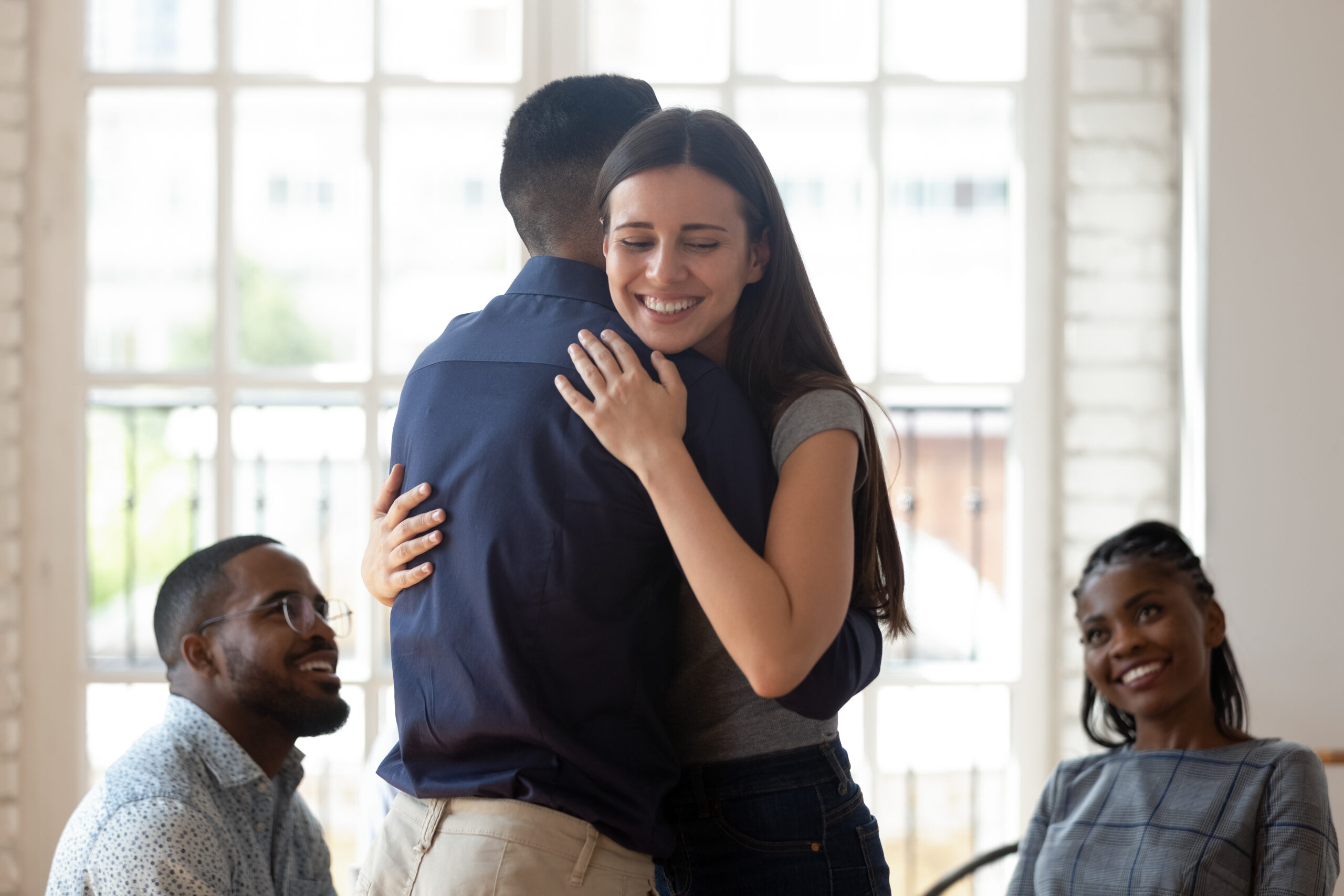 Relieved happy man and woman embrace give support during therapy