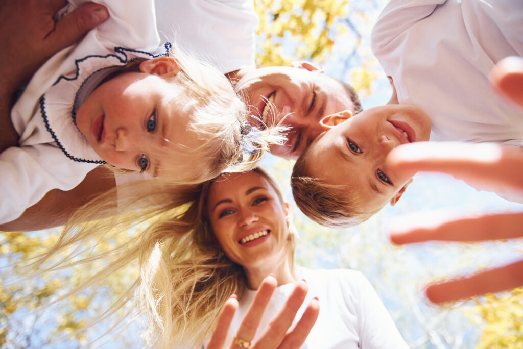 Happy family in autumn park looks down into the camera