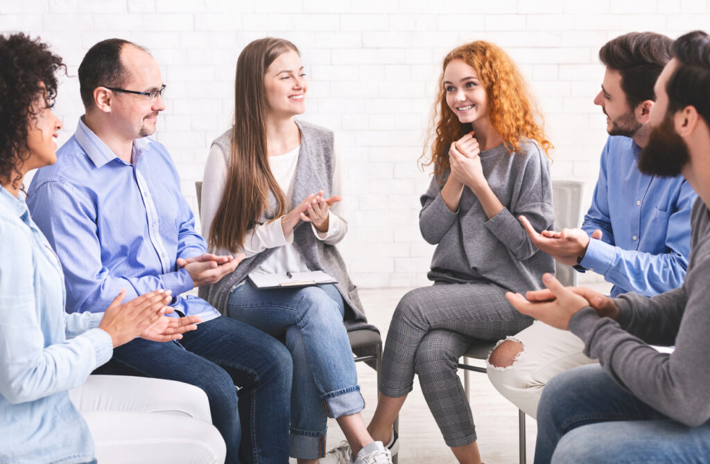 People applauding to young woman at therapy session in rehab