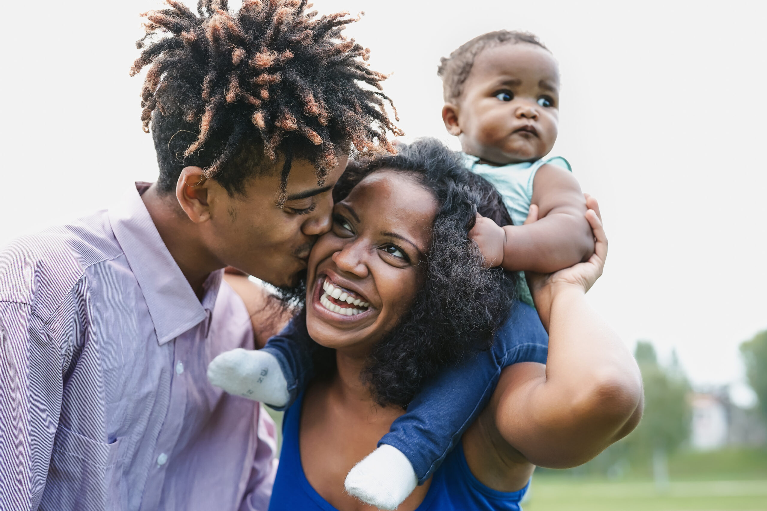 Happy African family having fun together in public park - Black father and mother enjoying weekend with their daughter - People love and parent unity concept