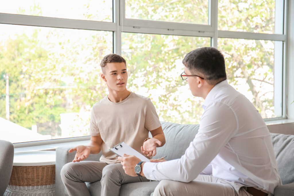 Psychologist working with teenage boy in office