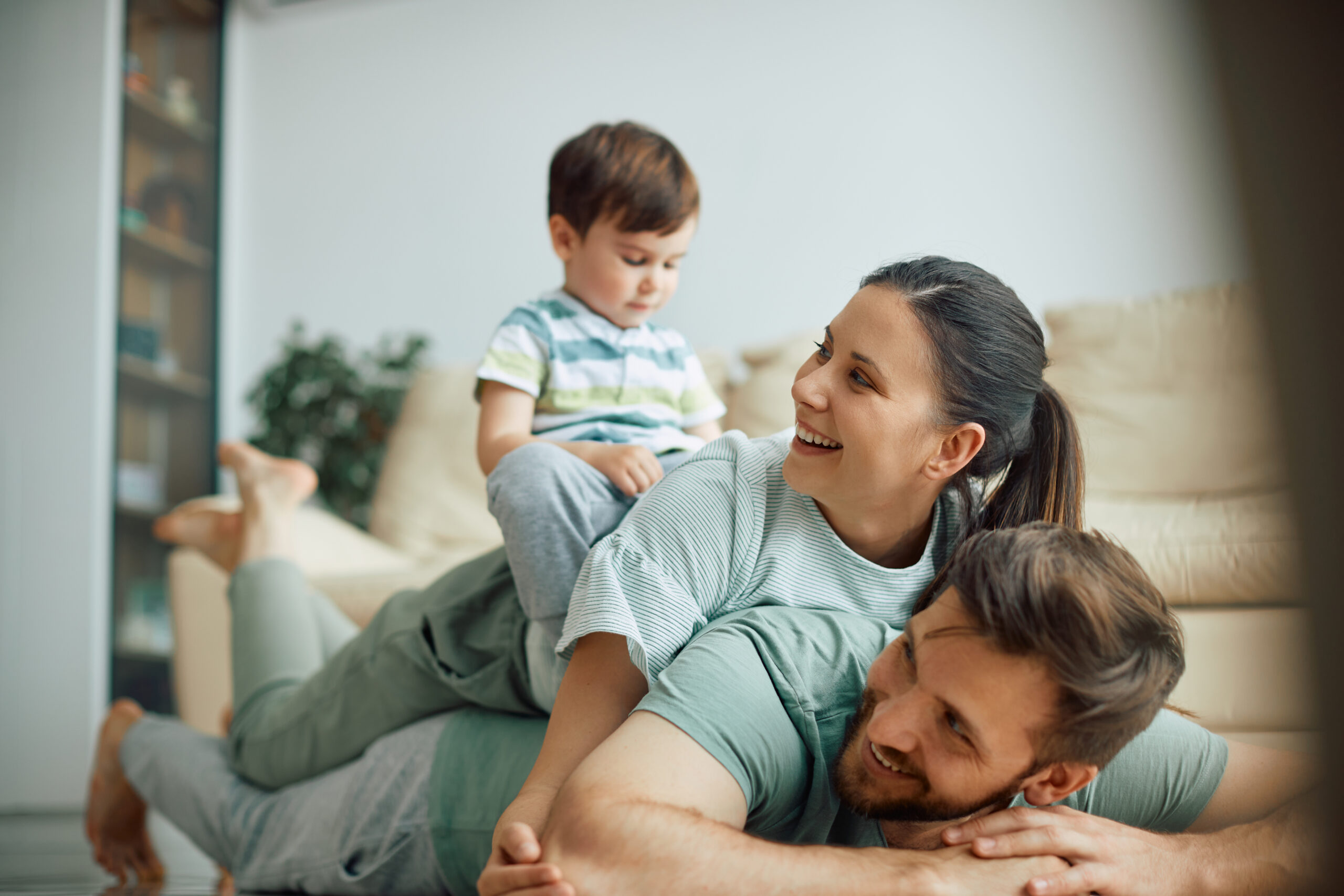 Happy family has fun while making human pyramid on the floor at home.