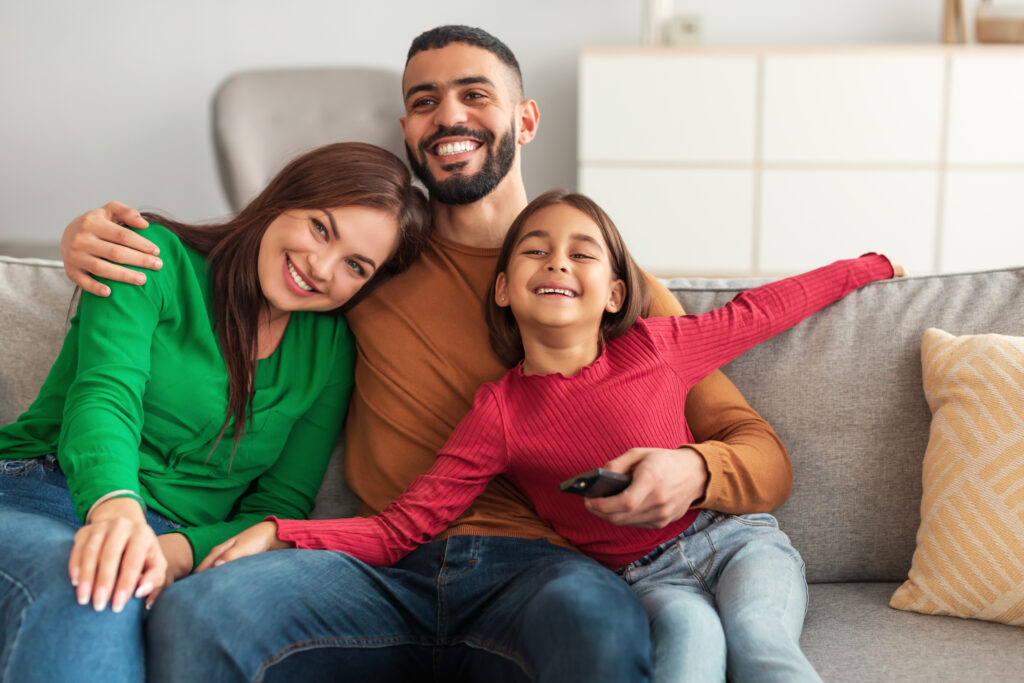 Happy young family watching television sitting on sofa