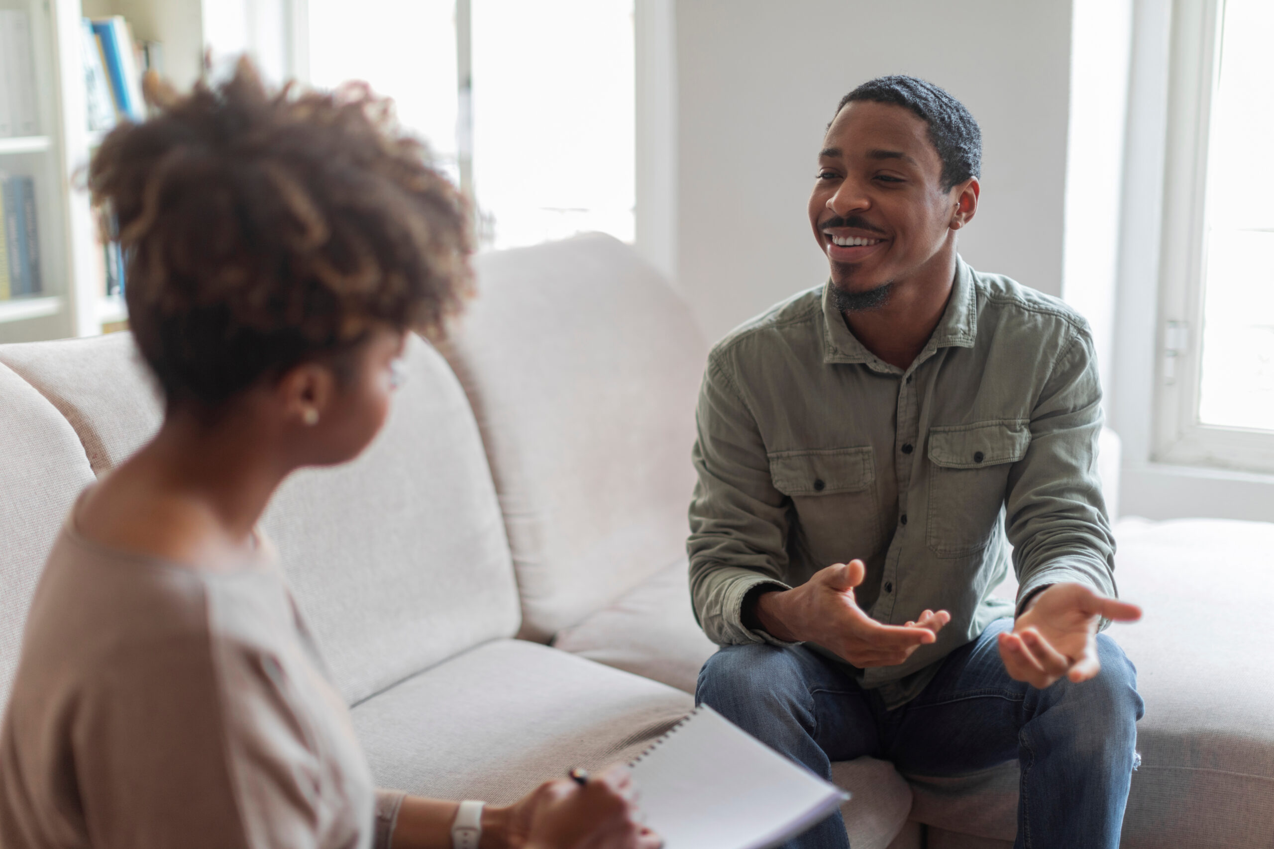 Cheerful positive african american guy having conversation with therapist